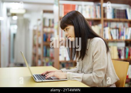 Studentinnen, die Computer in der Bibliothek benutzen Stockfoto