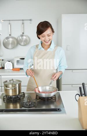 Frau in Schürze, die Fleisch grillt Stockfoto