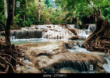 Glatte Felsen mit kaskadierendem Wasser bilden eine Reihe von schönen kurzen Wasserfällen im dichten Wald des Nationalparks. Kuang Si Wasserfälle in Luang Proba Stockfoto