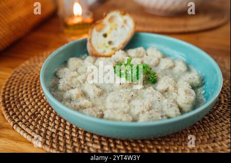 Trüffel-Gnocchi in cremiger Sauce mit Brot auf einem rustikalen Tisch Stockfoto