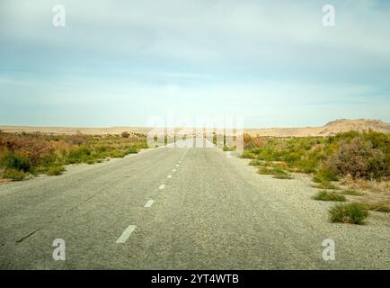 Eine alte Asphaltstraße mitten in der Wüste Kyzylkum. Stockfoto