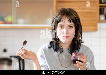 Eine junge Frau isst Marmelade in der Küche Stockfoto