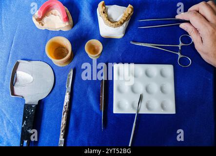 Draufsicht auf zahnärztliche Instrumente und Prothesenformen auf blauer Oberfläche. Stockfoto