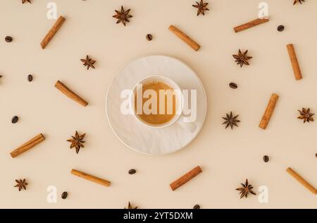 Kreatives trendiges Muster aus Kaffeebohnen, Zimtstangen und Sternanis mit einer Tasse Kaffee auf pastellfarbenen cremefarbenen Hintergrund. Minimales Kaffeekonzept. Stockfoto