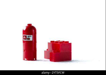 Ein roter Lego-Stein befindet sich neben einem roten Hydranten. Der Hydrant ist rot und mit einem weißen Etikett versehen. Lego. Polen, Warschau 06.12.2024 Stockfoto