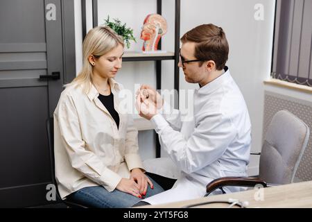 Ein junger attraktiver Hals-Nasen-Ohren-Arzt berät eine Patientin. Ein Arzt erklärt einer Frau, wie man ein Hörgerät trägt. Stockfoto