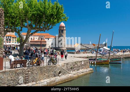 Collioure (Südfrankreich): Touristen, traditionelle Boote und Blick auf die Stadt mit dem ehemaligen Leuchtturm, heute der Glockenturm der Kirche Notre-da Stockfoto