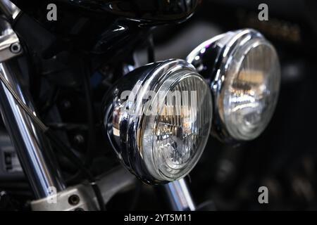 Runde Frontscheinwerfer eines glänzend schwarzen Straßenmotorrads, Nahaufnahme mit selektivem Fokus Stockfoto