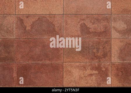 Granitfliesenwand, Ziegel, Gedenktafel. Sogar rechteckige rote Blöcke, Hintergrund. Glatte Oberfläche aus behandeltem Naturstein. Stockfoto