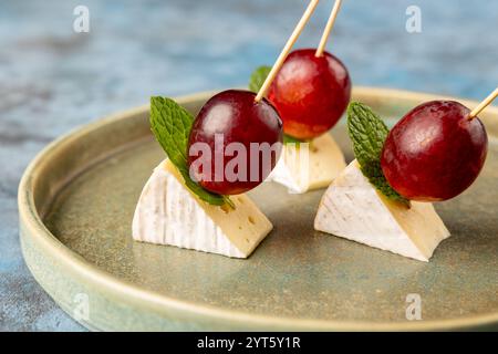 Der Snack besteht aus Stücken Brie-Käse und Trauben auf Zahnstochern. Restaurantservice Stockfoto