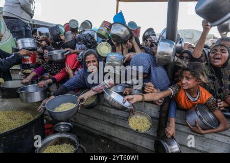 Khan Younis, Palästinensische Gebiete. Dezember 2024. Vertriebene Palästinenser überschwemmen sich, um Mahlzeiten aus der Rafah Charitable Kitchen (Tekia) in Khan Younis zu erhalten. Die Vereinten Nationen und internationale Organisationen warnen vor einer Hungersnot im Gazastreifen und fordern alle Konfliktparteien, palästinensischen Fraktionen und die israelische Regierung nachdrücklich auf, die Einfahrt von Hilfsfahrzeugen in den Gazastreifen zu gestatten und ihre Missionen zu erleichtern, um eine humanitäre Katastrophe im Gazastreifen aufgrund des anhaltenden Konflikts zwischen Israel und der Hamas zu vermeiden. Abed Rahim Khatib/dpa/Alamy Live News Stockfoto