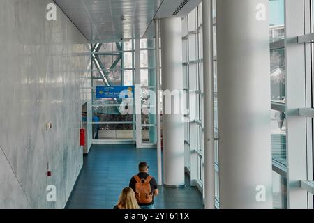 Marseille. Frankreich - 06. Dezember 2024: Ein moderner Korridor in einem Kreuzfahrtterminal, in dem Passagiere in Richtung Gepäckausgabe gehen, mit klarem Licht Stockfoto