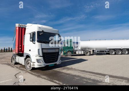 Zwei lange Lastwagen mit zehn Rädern, einer mit einem Tankwagen, parken auf dem Parkplatz. Nutzfahrzeuge, Werbung für Fahrzeuge für den Gütertransport. Fo Stockfoto