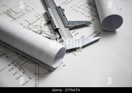Der Messschieber liegt auf gerollten Blaupausen auf und unterstreicht die Bedeutung präziser Messungen in der Konstruktion und Konstruktion. Stockfoto