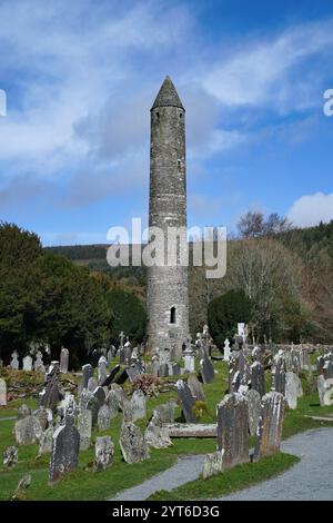 Rundturm und Friedhof des ehemaligen mittelalterlichen Klosters in Glendalough, Irland Stockfoto