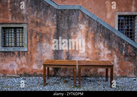 Zwei Vintage-Holztische vor einer antiken Hausfassade. Udine City, Friaul Julisch Venetien, Italien. Minimales Kompositionsbild mit Kopierraum. Stockfoto