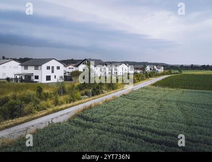 Blick auf Einfamilienhäuser in einem Neubaugebiet am Ortsrand mit Grün und einem Getreidefeld im Vordergrund Stockfoto