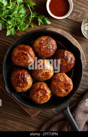 Gehacktes Schweinefleisch und Rindfleisch in gusseiserner Pfanne auf hölzernem Hintergrund. Draufsicht, flach Stockfoto