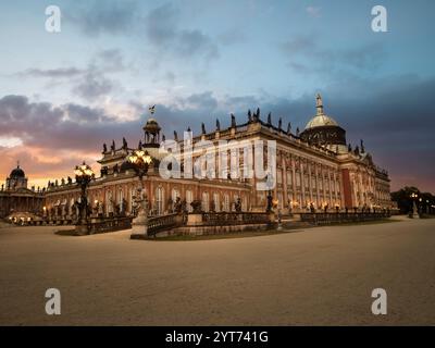 Abendblick auf Schloss Sanssouci und Neuen Palast in Potsdam, Deutschland, mit barocker Architektur, beleuchtet durch sanfte Beleuchtung und einem ruhigen Abendhimmel Stockfoto