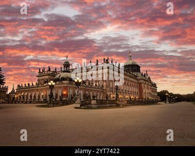 Atemberaubender Blick auf Schloss Sanssouci mit dem Neuen Schloss in Potsdam, Deutschland, mit barocker Architektur und beleuchteten Details vor einem lebhaften Abendhimmel Stockfoto