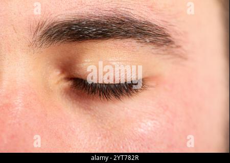 Extreme Nahaufnahme des geschlossenen Lids mit Wimpern und Augenbrauen des jungen Mannes Stockfoto