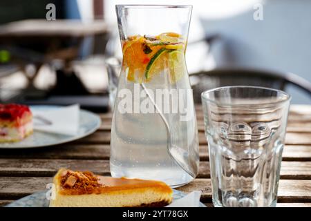 Krug mit Fruchtwasser, Glas und Karamellkuchen auf dem Tisch. Stockfoto