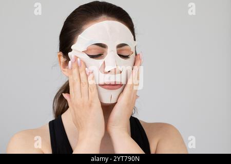 Die schöne Frau trägt eine feuchtigkeitsspendende Maske auf ihr Gesicht auf Stockfoto