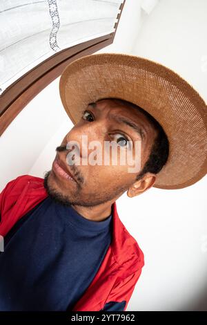 Porträt eines neugierigen Mannes, der einen Strohhut trägt und einen lustigen Gesichtsausdruck erzeugt Stockfoto