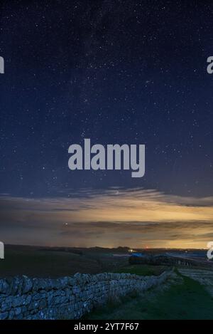 Ein Sternenhimmel, der von Winshield Crags aus gesehen wird, entlang der Linie der Hadrian's Wall, Northumberland, Großbritannien. Milchstraße, Jupiter und Pleiades Cluster. Stockfoto