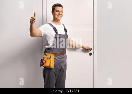 Der Reparaturmann öffnet eine Tür und drückt die Daumen hoch Stockfoto