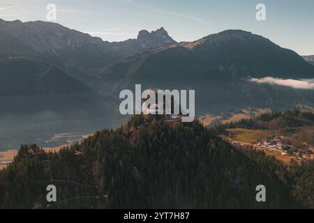 Die Ruine der Burg Falkenstein bei Pfronten im Allgäu. Umgeben von Wald steht die Burg auf einem Hügel, während Nebel im Tal liegt. Die Berge des Alpenvorlandes im Hintergrund. Stockfoto