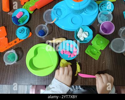 Das Kind formt Weichplastilin, spielt am Tisch mit einer Reihe von Formen und einem Messer. Lernspiele. Stockfoto