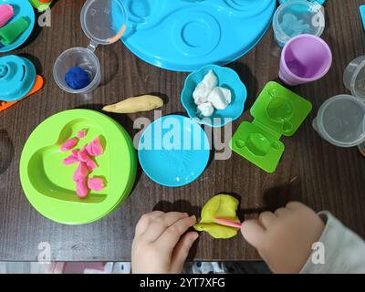 Das Kind formt Weichplastilin, spielt am Tisch mit einer Reihe von Formen und einem Messer. Lernspiele. Stockfoto