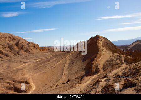 Malerischer Blick auf eine zerklüftete Wüstenlandschaft mit einem schmalen Bergweg in Valle de la Luna, San Pedro de Atacama, Chile, unter einem klaren blauen Himmel Stockfoto