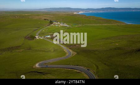 FEBRUAR 2023, POINT REYES NATIONAL SEASHORE, KALIFORNIEN, USA - Vogelperspektive Panoramablick auf die kurvige Straße in Point Reyes mit sanften grünen Hügeln und Meereswellen Stockfoto