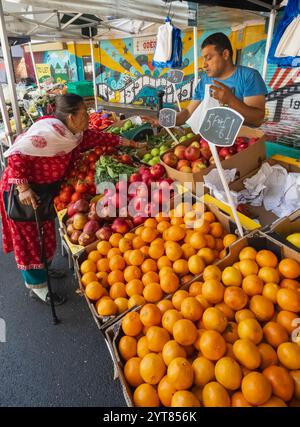 England, Kent, Ashford, Ashford Town Centre, Frau in traditioneller nepalesischer Kleidung, die Obst am Straßenstand kauft Stockfoto