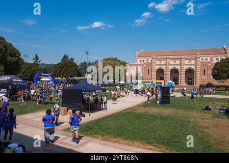 Eine große Menschenmenge versammelt sich auf der Grasfläche der UCLA zu einem Festival. Die romanische Architektur der Royce Hall ist sichtbar, mit Zelten und farbenfrohen Uniformen. Stockfoto