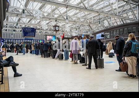 Passagiere, die sich in der Warteschlange in der Halle des Glasgow Central Station befinden und an Bord eines verspäteten Zuges nach London Euston, Glasgow, Schottland, Großbritannien, Europa warten Stockfoto