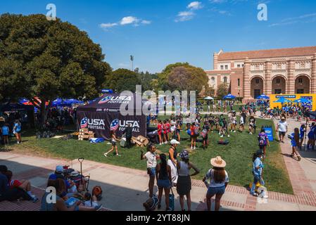 Auf dem grasbewachsenen Campus der UCLA, der von historischen Gebäuden umgeben ist, versammeln sich zahlreiche Menschenmengen. Ein USA Football Zelt und verschiedene Sitzplätze sorgen für eine festliche Atmosphäre. Stockfoto