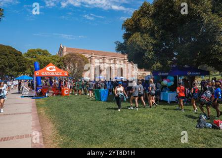 Eine große Menschenmenge versammelt sich auf der Grasfläche der UCLA zu einer festlichen Veranstaltung. Die Szene umfasst ein Gatorade-Zelt, Ballons und die Backsteinfassade der Universität Stockfoto