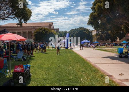 Eine große Gruppe versammelt sich auf der Grasfläche der UCLA zu einer Messe, umgeben von Zelten und klassischen Stiftsmauerbauten unter einem klaren blauen Himmel. Stockfoto