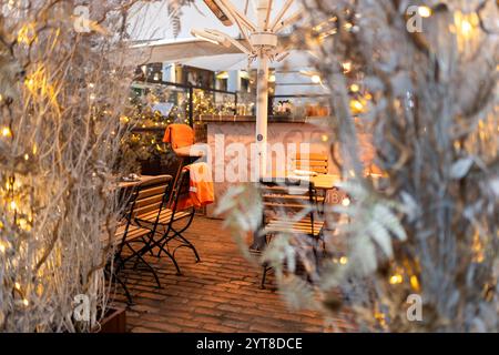 London, Großbritannien - 25. November 2024, Eingang zu einem Straßencafé in Covent Garden mit Tischen und Stühlen, die mit orangen Decken bedeckt sind, dekoriert für Chri Stockfoto