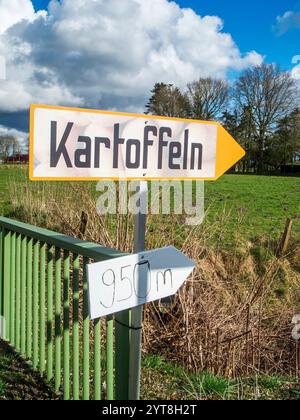 Schild für einen Kartoffelverkauf auf einer Landstraße in Ostfriesland unter blauem Himmel mit großen weißen Wolken. Stockfoto