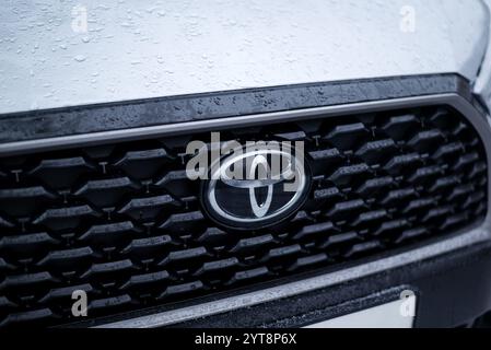 Kiew, Ukraine. 6. Dezember 2024. Nahaufnahme eines Toyota-Kühlergrills mit Regentropfen, das das legendäre Logo und das elegante Design an einem regnerischen Tag zeigt Stockfoto