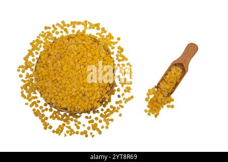 Eine Korbschale gefüllt mit gelben Linsen, begleitet von einem Holzlöffel, umgeben von gelben Linsenkörnern. Stockfoto