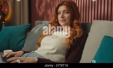 Kaukasische Frau Ginger Mädchen weibliche Studentin Geschäftsfrau Hausbesitzerin arbeitet online studieren mit Laptop Computer auf Sofa lächelnde fröhliche Dame Stockfoto