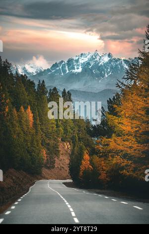 Straße auf dem Col d'Izoard in den französischen Alpen in Richtung Pics de La Font Sancte, Abendhimmel, Lärchen in Herbstfarben, vertikal Stockfoto