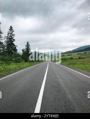 Leere Straße in den Bergen. Fluchtpunkt - Straße in den karpaten an einem bewölkten Tag. Stockfoto