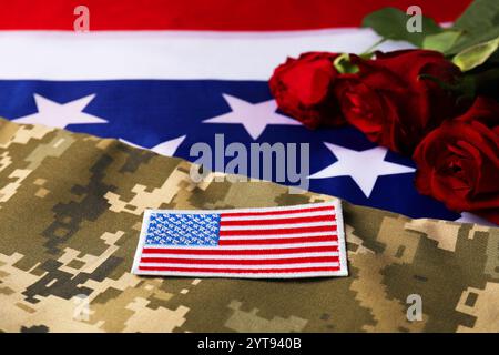 Veteranentag. US Army Patch, Rosenblumen und Militäruniform auf amerikanischer Flagge, Nahaufnahme Stockfoto