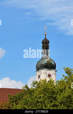 Der Turm der Pfarrkirche Mariä Himmelfahrt in Bad Kötzting, Oberpfalz, blickt hinter Bäumen hervor Stockfoto